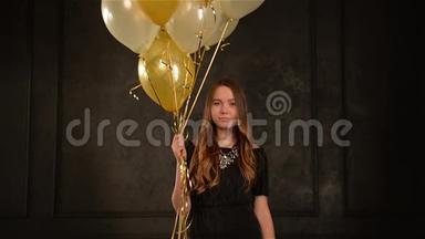 派对女郎手中拿着空气气球站在金色和银色的纸屑中。 长发少女微笑